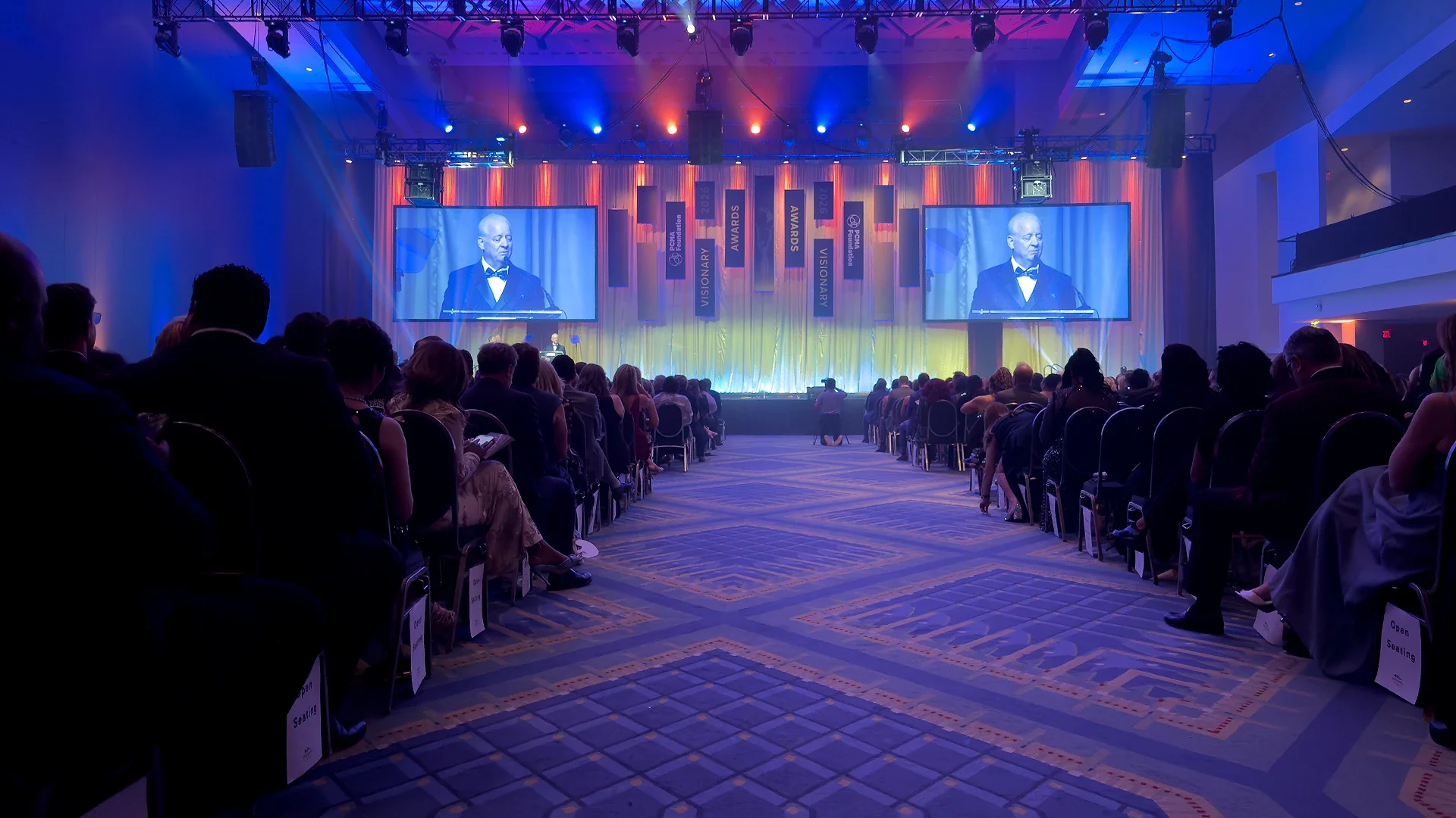 Professional corporate conference staging with LED screens, branded lectern and tiered seating