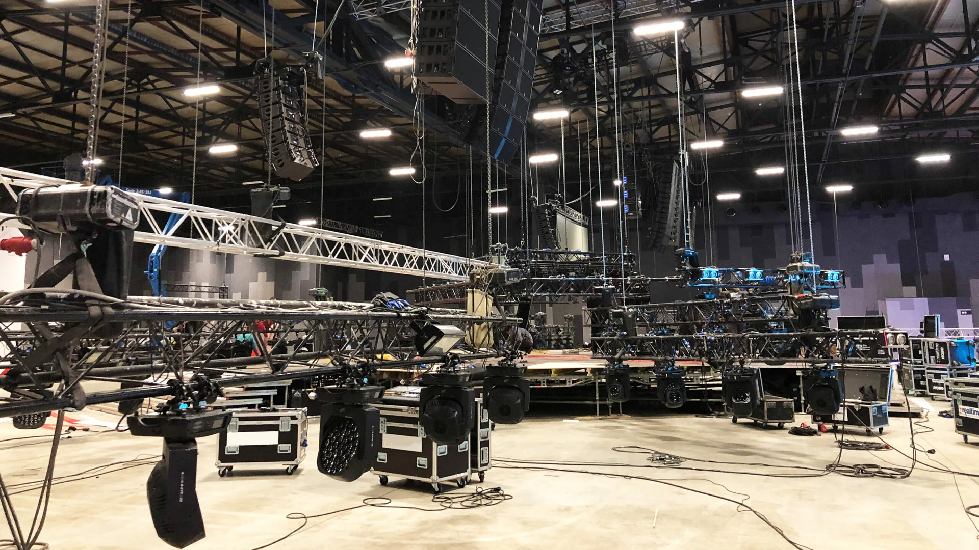 Event production crew rigging truss and cabling backstage before a live show