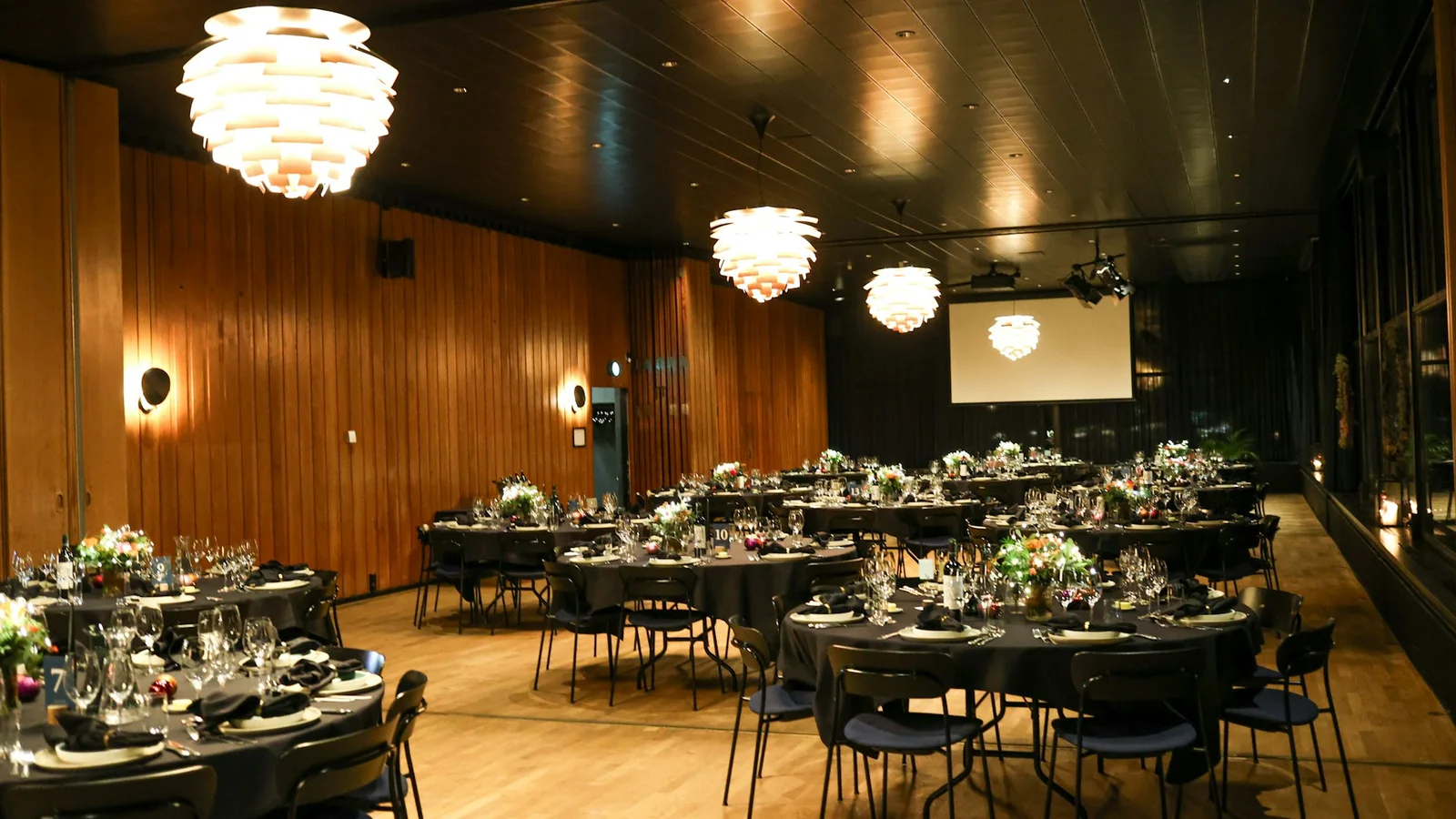 An elegant event room set with round banquet tables, flowers and glassware
