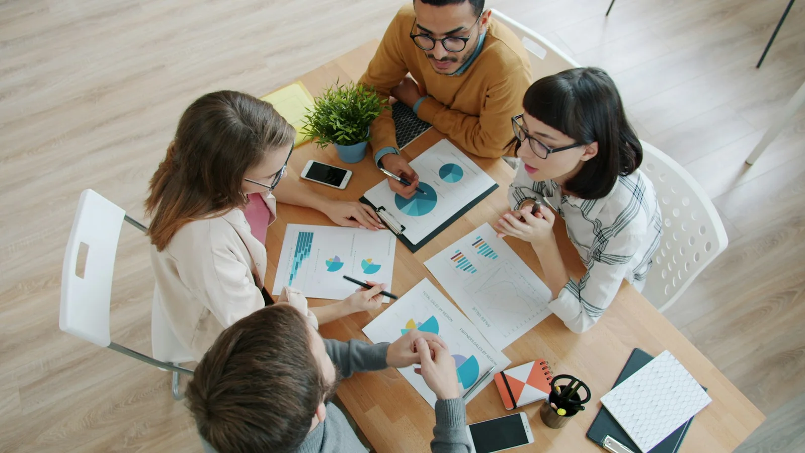 A planning team collaborating around a table of printed charts and documents
