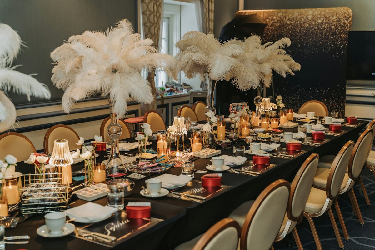 Great Gatsby theme: an art-deco banquet table with feather centrepieces in gold and black