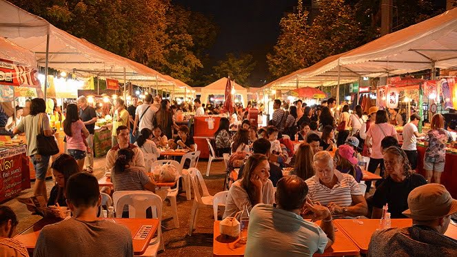 A crowd of people at an outdoor market organized by an event company in Johannesburg at night.